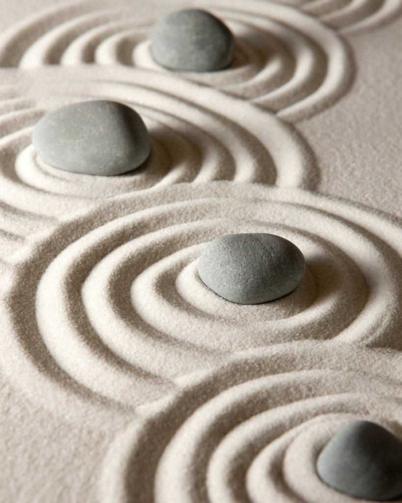 Composition zen avec sable texturé et pierres naturelles représentant l’équilibre émotionnel, le recentrage mental, la récupération nerveuse et l’approche holistique du bien-être développée par NÛMA.